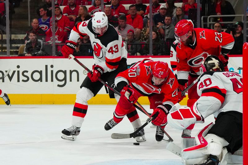 May 11, 2023; Raleigh, North Carolina, USA; New Jersey Devils defenseman Luke Hughes (43) and Carolina Hurricanes center Sebastian Aho (20) battle over the puck during the third period in game five of the second round of the 2023 Stanley Cup Playoffs at PNC Arena. Mandatory Credit: James Guillory-USA TODAY Sports