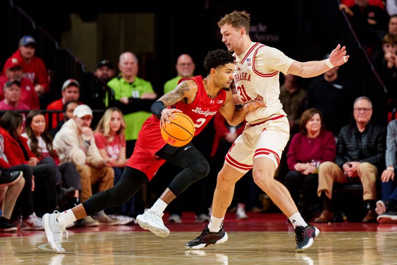 Dec 10, 2025; Lincoln, Nebraska, USA; Wisconsin Badgers guard Nick Boyd (2) drives against Nebraska Cornhuskers forward Pryce Sandfort (21) during the first half at Pinnacle Bank Arena. Mandatory Credit: Dylan Widger-Imagn Images