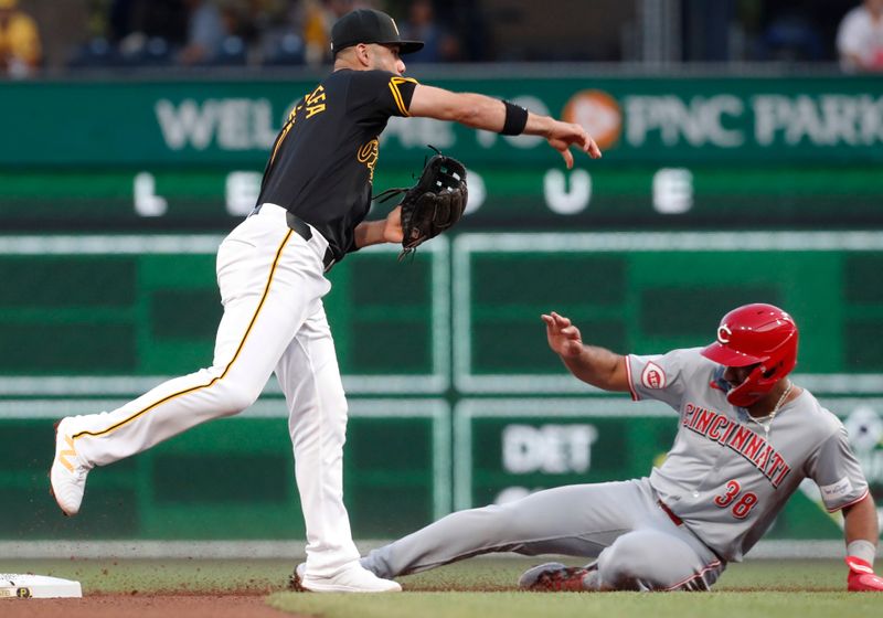 Aug 22, 2024; Pittsburgh, Pennsylvania, USA;  Pittsburgh Pirates third baseman Isiah Kiner-Falefa (7) throws to first base to complete a double play over Cincinnati Reds right fielder Amed Rosario (38) during the fifth inning at PNC Park. Mandatory Credit: Charles LeClaire-USA TODAY Sports