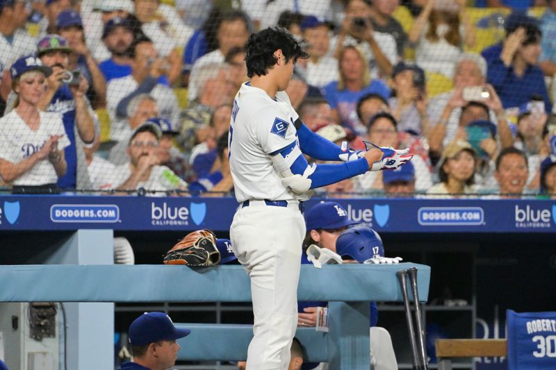 Sep 16, 2025; Los Angeles, California, USA; Los Angeles Dodgers two-way player Shohei Ohtani (17)switches to batting gear after striking out Philadelphia Phillies center fielder Brandon Marsh (16) during the first inning at Dodger Stadium. Mandatory Credit: Jayne Kamin-Oncea-Imagn Images