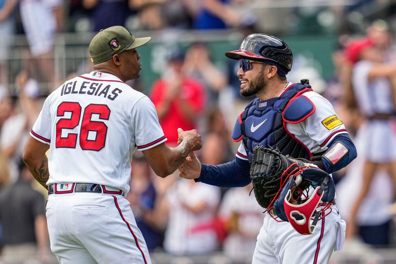 May 21, 2023; Cumberland, Georgia, USA; Atlanta Braves relief pitcher Raisel Iglesias (26) reacts with catcher Travis d'Arnaud (16) after the Braves defeated the Seattle Mariners at Truist Park. Mandatory Credit: Dale Zanine-USA TODAY Sports