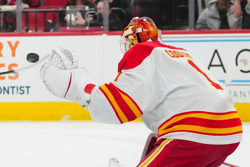 Nov 30, 2025; Raleigh, North Carolina, USA;  Calgary Flames goaltender Devin Cooley (1) watches the shot against the Carolina Hurricanes during the first period at Lenovo Center. Mandatory Credit: James Guillory-Imagn Images