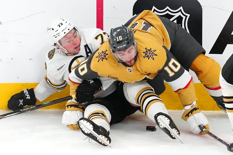 Jan 11, 2024; Las Vegas, Nevada, USA; Boston Bruins defenseman Charlie McAvoy (73) and Vegas Golden Knights center Nicolas Roy (10) fall to the ice during the third period at T-Mobile Arena. Mandatory Credit: Stephen R. Sylvanie-USA TODAY Sports