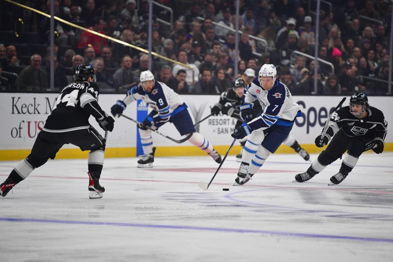 Dec 13, 2023; Los Angeles, California, USA; Winnipeg Jets center Vladislav Namestnikov (7) moves the puck against Los Angeles Kings center Phillip Danault (24) and defenseman Mikey Anderson (44) during the first period at Crypto.com Arena. Mandatory Credit: Gary A. Vasquez-USA TODAY Sports