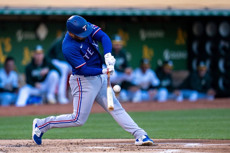 Aug 8, 2023; Oakland, California, USA;  Texas Rangers shortstop Ezequiel Duran (20) hits a RBI single against the Oakland Athletics during the second inning at Oakland-Alameda County Coliseum. Mandatory Credit: Neville E. Guard-USA TODAY Sports