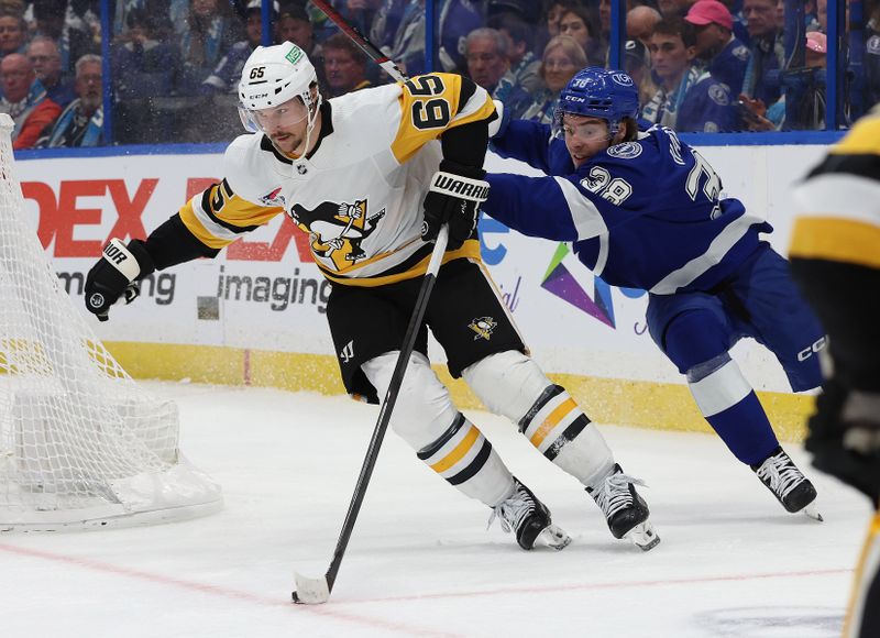 Dec 6, 2023; Tampa, Florida, USA; Pittsburgh Penguins defenseman Erik Karlsson (65) skates with the puck as Tampa Bay Lightning left wing Brandon Hagel (38) defends during the third period at Amalie Arena. Mandatory Credit: Kim Klement Neitzel-USA TODAY Sports