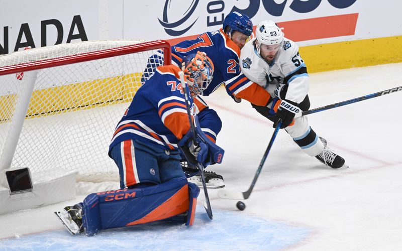 Dec 31, 2024; Edmonton, Alberta, CAN;  Edmonton Oilers goalie Stuart Skinner (74) battles for the puck with Utah Hockey Club left winger Michael Carcone (53) and Oilers defenceman Brett Kulak (27) during the third period at Rogers Place. Mandatory Credit: Walter Tychnowicz-Imagn Images