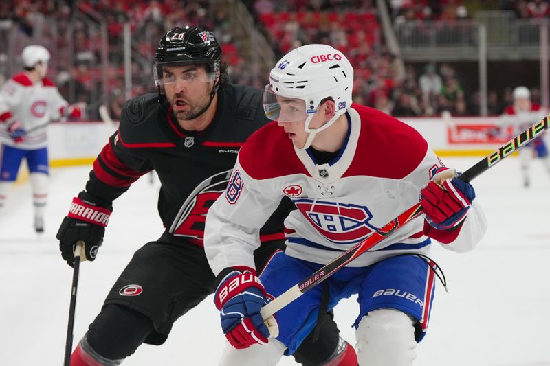 Jan 1, 2026; Raleigh, North Carolina, USA;  Montréal Canadiens defenseman Lane Hutson (48) and Carolina Hurricanes left wing William Carrier (28) chase after the puck during the first period at Lenovo Center. Mandatory Credit: James Guillory-Imagn Images
