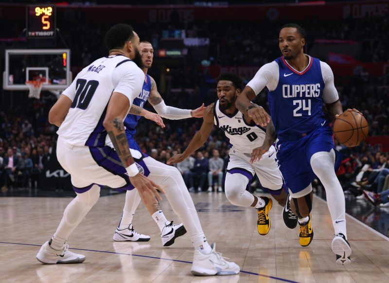 LOS ANGELES, CALIFORNIA - DECEMBER 12: Norman Powell #24 of the LA Clippers dribbles between Malik Monk #0 and JaVale McGee #00 of the Sacramento Kings as Daniel Theis #10 rolls out of a screen during a 119-99 Clippers win at Crypto.com Arena on December 12, 2023 in Los Angeles, California.  NOTE TO USER: User expressly acknowledges and agrees that, by downloading and or using this photograph, User is consenting to the terms and conditions of the Getty Images License Agreement. (Photo by Harry How/Getty Images)