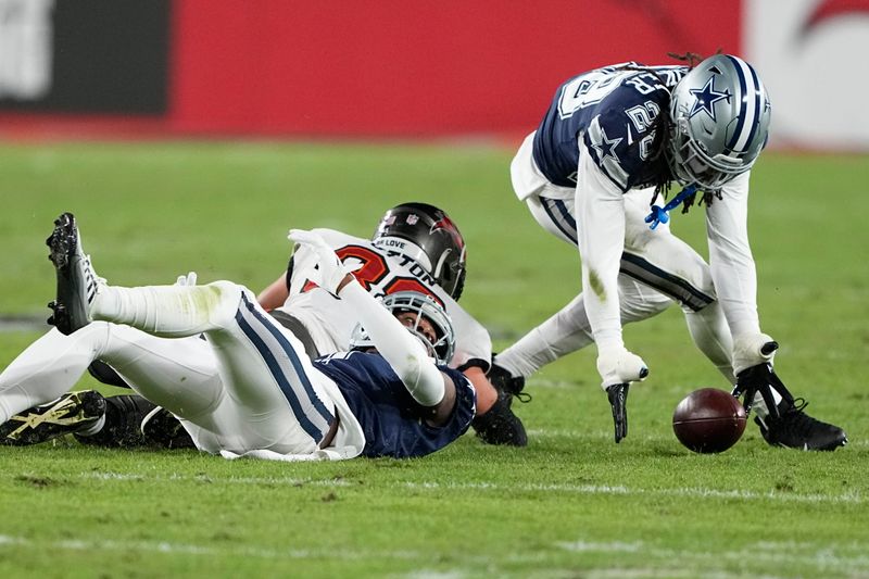 Dallas Cowboys safety Malik Hooker (28) picks up a fumble from Tampa Bay Buccaneers tight end Cade Otton (88) during the second half of an NFL wild-card football game, Monday, Jan. 16, 2023, in Tampa, Fla. The fumble was over ruled on a replay. (AP Photo/Chris Carlson)