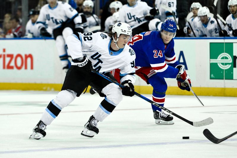 Oct 12, 2024; New York, New York, USA; Utah Hockey Club center Logan Cooley (92) skates with the puck against New York Rangers right wing Kaapo Kakko (24) during the third period at Madison Square Garden. Mandatory Credit: John Jones-Imagn Images