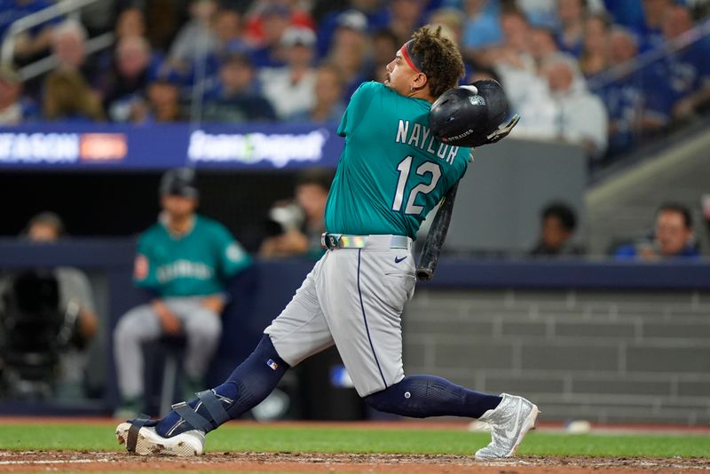 Oct 12, 2025; Toronto, Ontario, CAN; Seattle Mariners first baseman Josh Naylor (12) loses his helmet on a swing against the Toronto Blue Jays in the eighth inning during game one of the ALCS round for the 2025 MLB playoffs at Rogers Centre. Mandatory Credit: John E. Sokolowski-Imagn Images