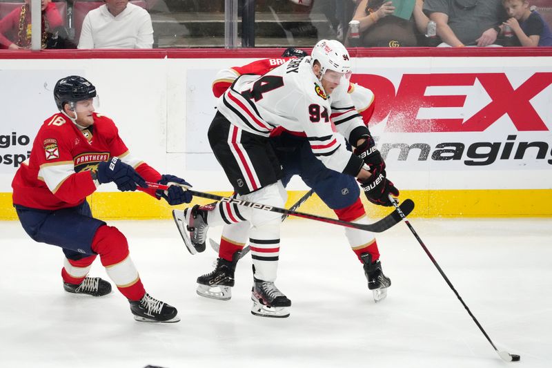 Nov 12, 2023; Sunrise, Florida, USA; Florida Panthers center Steven Lorentz (18) reaches for the puck on Chicago Blackhawks right wing Corey Perry (94) during the third period at Amerant Bank Arena. Mandatory Credit: Jasen Vinlove-USA TODAY Sports