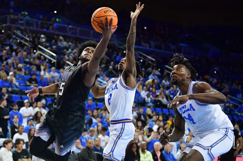 January 14, 2024; Los Angeles, California, USA; Washington Huskies guard Sahvir Wheeler (5) moves to the basket against UCLA Bruins guard Dylan Andrews (2) and forward Kenneth Nwuba (14) during the first half at Pauley Pavilion. Mandatory Credit: Gary A. Vasquez-USA TODAY Sports