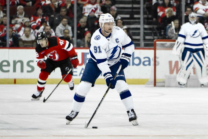 Feb 25, 2024; Newark, New Jersey, USA; Tampa Bay Lightning center Steven Stamkos (91) skates with the puck as \New Jersey Devils left wing Brian Halonen (48) trails during the first period at Prudential Center. Mandatory Credit: John Jones-USA TODAY Sports