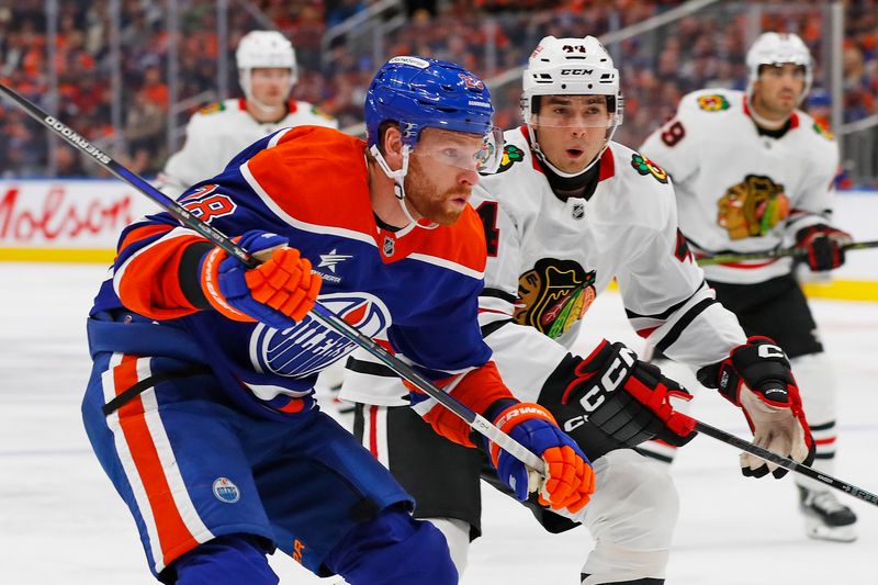 Oct 12, 2024; Edmonton, Alberta, CAN; Edmonton Oilers forward Connor Brown (28) and Chicago Blackhawks defensemen Wyatt Kaiser (44) chase a loose puck during the first period at Rogers Place. Mandatory Credit: Perry Nelson-Imagn Images