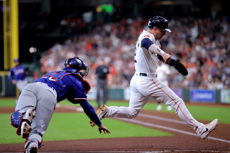 Jul 13, 2024; Houston, Texas, USA; Houston Astros third baseman Alex Bregman (2) avoids a tag attempt by Texas Rangers catcher Jonah Heim (28) while crossing home plate to score a run during the first inning at Minute Maid Park. Mandatory Credit: Erik Williams-USA TODAY Sports