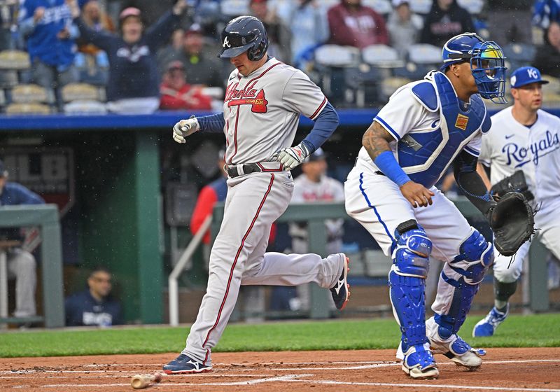 Apr 15, 2023; Kansas City, Missouri, USA;  Atlanta Braves third baseman Austin Riley (27) scores a run past Kansas City Royals catcher Salvador Perez (13) during the first inning at Kauffman Stadium. Mandatory Credit: Peter Aiken-USA TODAY Sports