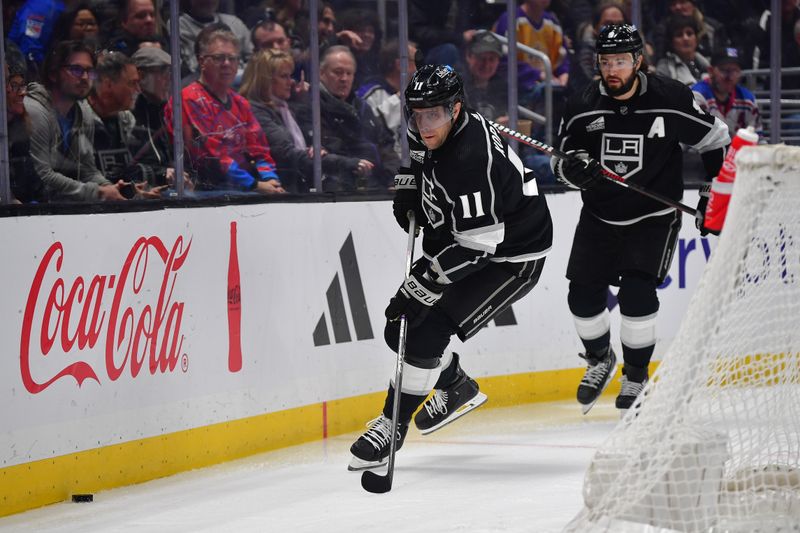 Jan 20, 2024; Los Angeles, California, USA; Los Angeles Kings center Anze Kopitar (11) moves the puck against the New York Rangers as defenseman Drew Doughty (8) trails durng the first period at Crypto.com Arena. Mandatory Credit: Gary A. Vasquez-USA TODAY Sports