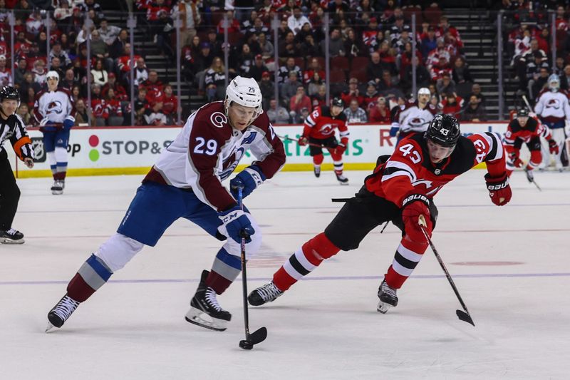 Feb 6, 2024; Newark, New Jersey, USA; Colorado Avalanche center Nathan MacKinnon (29) skates with the puck while being defended by New Jersey Devils defenseman Luke Hughes (43) during the third period at Prudential Center. Mandatory Credit: Ed Mulholland-USA TODAY Sports