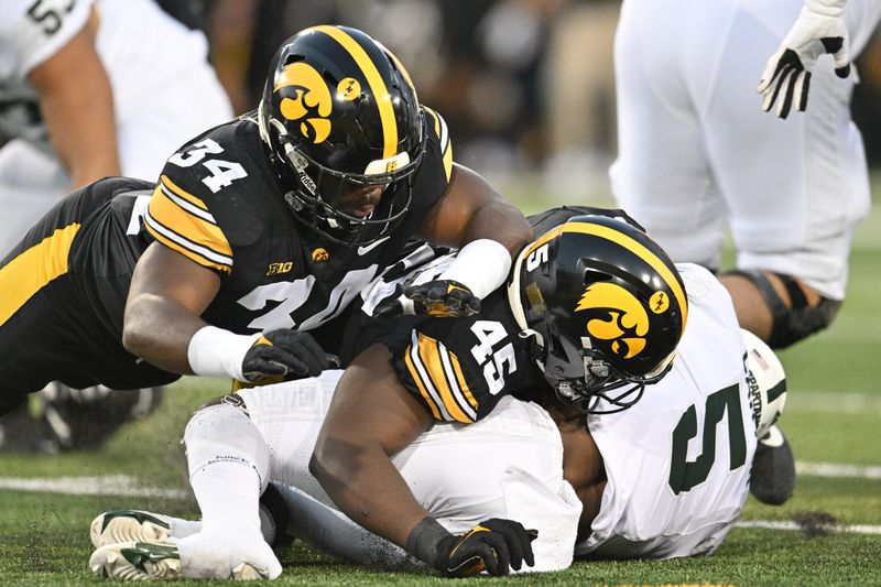 Sep 30, 2023; Iowa City, Iowa, USA; Iowa Hawkeyes linebacker Jay Higgins (34) and defensive lineman Deontae Craig (45) tackle Michigan State Spartans running back Nathan Carter (5) during the first quarter at Kinnick Stadium. Mandatory Credit: Jeffrey Becker-USA TODAY Sports