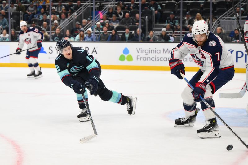 Nov 12, 2024; Seattle, Washington, USA; Seattle Kraken left wing Tye Kartye (12) defends Columbus Blue Jackets center Sean Kuraly (7) during the third period at Climate Pledge Arena. Mandatory Credit: Steven Bisig-Imagn Images