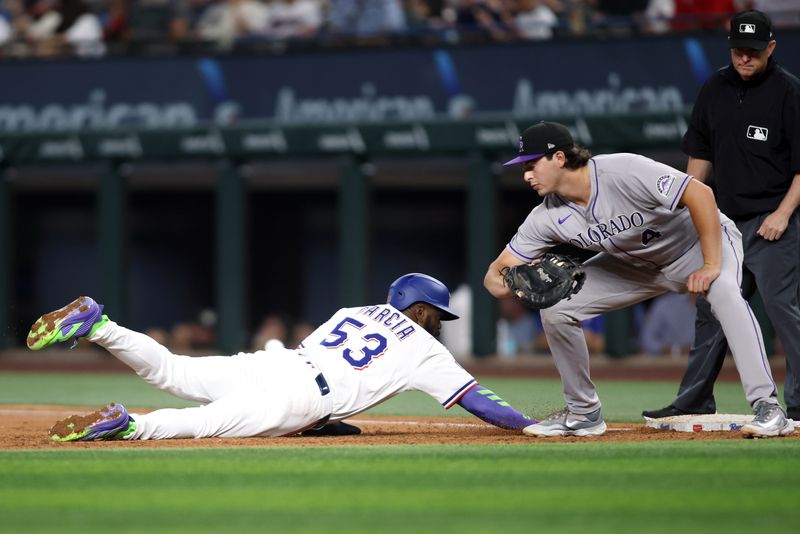 May 14, 2025; Arlington, Texas, USA; Texas Rangers outfielder Adolis García (53) dives back to first base as Colorado Rockies first base Michael Toglia (4) attempts to make the tag during the third inning at Globe Life Field. Mandatory Credit: Tim Heitman-Imagn Images