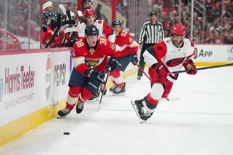 Sep 24, 2025; Raleigh, North Carolina, USA;  Florida Panthers right wing Jack Devine (38) skates after the puck against Carolina Hurricanes defenseman Shayne Gostisbehere (4) during the second period at Lenovo Center. Mandatory Credit: James Guillory-Imagn Images