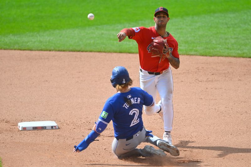 Jun 23, 2024; Cleveland, Ohio, USA; Cleveland Guardians shortstop Brayan Rocchio (4) turns a double play beside Toronto Blue Jays designated hitter Justin Turner (2) in the seventh inning at Progressive Field. Mandatory Credit: David Richard-USA TODAY Sports