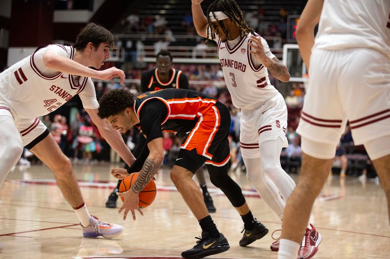 Feb 24, 2024; Stanford, California, USA; Oregon State Beavers guard Jordan Pope (0) gathers the ball between Stanford Cardinal defenders Maxime Raynaud (42) and  Kanaan Carlyle (3) during the first half at Maples Pavilion. Mandatory Credit: D. Ross Cameron-USA TODAY Sports