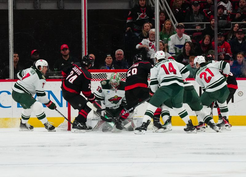 Jan 21, 2024; Raleigh, North Carolina, USA;  Minnesota Wild goaltender Filip Gustavsson (32) stops the scoring attempt by left wing Michael Bunting (58) and Carolina Hurricanes center Seth Jarvis (24) during the second period at PNC Arena. Mandatory Credit: James Guillory-USA TODAY Sports