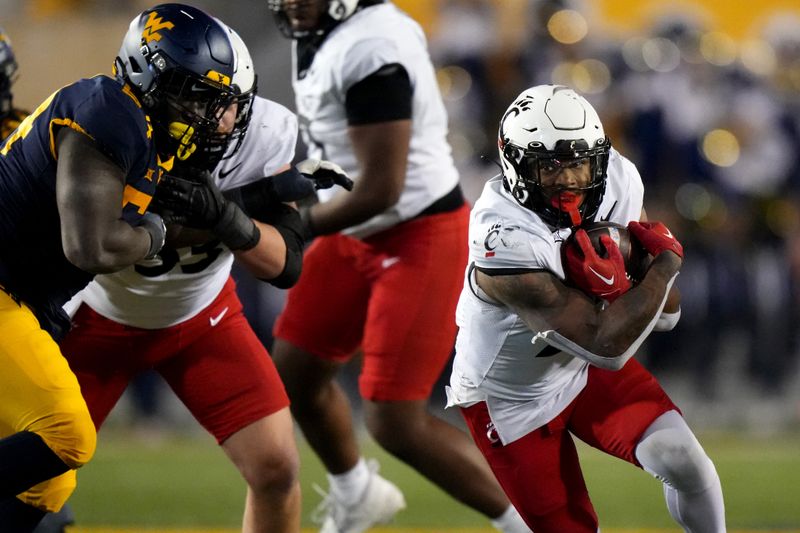 Nov 18, 2023; Morgantown, West Virginia, USA; Cincinnati Bearcats running back Corey Kiner (21) carries the ball against the West Virginia Mountaineers in the fourth quarter at Milan Puskar Stadium. West Virginia won 42-21. Mandatory Credit: Kareem Elgazzar-USA TODAY Sports