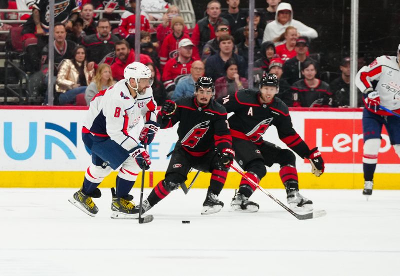 Nov 3, 2024; Raleigh, North Carolina, USA;  Washington Capitals left wing Alex Ovechkin (8) holds onto the puck against Carolina Hurricanes center Seth Jarvis (24) and  defenseman Jaccob Slavin (74) during the third period at Lenovo Center. Mandatory Credit: James Guillory-Imagn Images