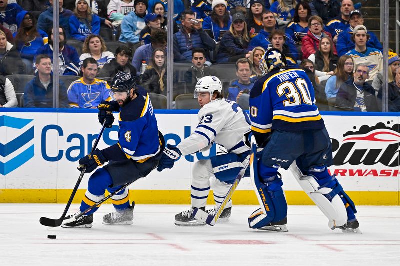 Feb 19, 2024; St. Louis, Missouri, USA;  St. Louis Blues goaltender Joel Hofer (30) and defenseman Nick Leddy (4) controls the puck against Toronto Maple Leafs left wing Matthew Knies (23) during the third period at Enterprise Center. Mandatory Credit: Jeff Curry-USA TODAY Sports