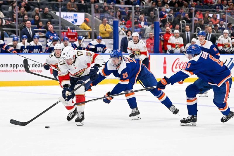 Jan 27, 2024; Elmont, New York, USA; Florida Panthers center Evan Rodrigues (17) skates with the puck defended by New York Islanders defenseman Alexander Romanov (28) and New York Islanders defenseman Noah Dobson (8) during the first period at UBS Arena. Mandatory Credit: Dennis Schneidler-USA TODAY Sports