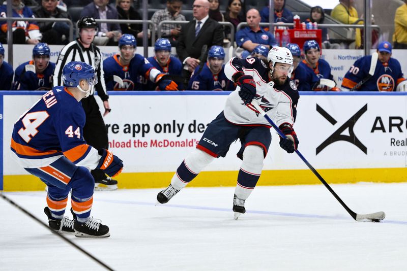 Dec 7, 2023; Elmont, New York, USA; Columbus Blue Jackets defenseman Ivan Provorov (9) passes the puck as New York Islanders center Jean-Gabriel Pageau (44) defends during the first period at UBS Arena. Mandatory Credit: John Jones-USA TODAY Sports