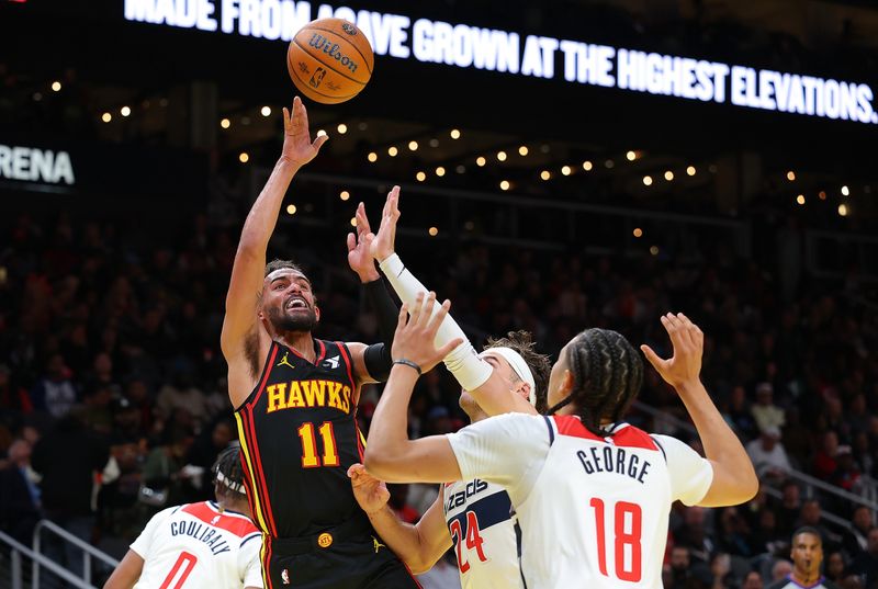 ATLANTA, GEORGIA - NOVEMBER 15:  Trae Young #11 of the Atlanta Hawks passes the ball against Corey Kispert #24 and Kyshawn George #18 of the Washington Wizards during the third quarter of the Emirates NBA Cup game at State Farm Arena on November 15, 2024 in Atlanta, Georgia.  NOTE TO USER: User expressly acknowledges and agrees that, by downloading and/or using this photograph, user is consenting to the terms and conditions of the Getty Images License Agreement.  (Photo by Kevin C. Cox/Getty Images)