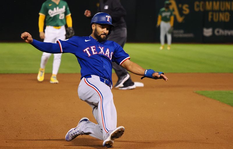 Sep 25, 2024; Oakland, California, USA; Texas Rangers second baseman Marcus Semien (2) slides safely to third base against the Oakland Athletics during the fourth inning at Oakland-Alameda County Coliseum. Mandatory Credit: Kelley L Cox-Imagn Images