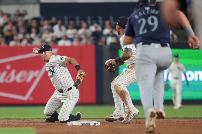 May 21, 2024; Bronx, New York, USA; New York Yankees shortstop Anthony Volpe (11) attempts to throw the ball to first base as Seattle Mariners catcher Cal Raleigh (29) runs to second base during the eighth inning at Yankee Stadium. Mandatory Credit: Vincent Carchietta-USA TODAY Sports