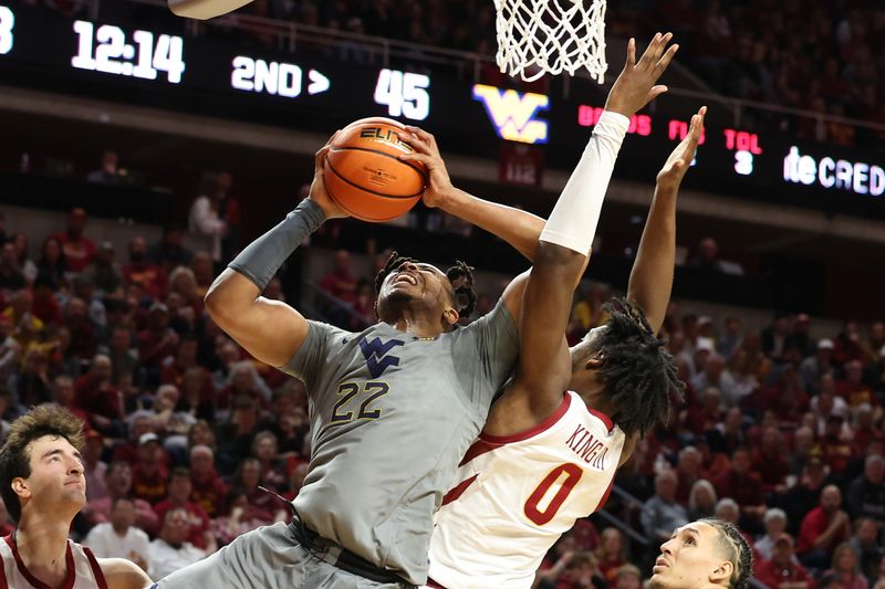 Feb 24, 2024; Ames, Iowa, USA; West Virginia Mountaineers forward Josiah Harris (22) shoots a layup over Iowa State Cyclones forward Tre King (0) during the second half at James H. Hilton Coliseum. Mandatory Credit: Reese Strickland-USA TODAY Sports