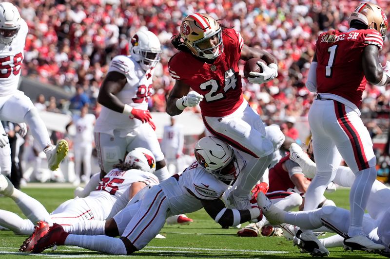 San Francisco 49ers running back Jordan Mason (24) runs against Arizona Cardinals safety Budda Baker, bottom, during the first half of an NFL football game in Santa Clara, Calif., Sunday, Oct. 6, 2024. (AP Photo/Godofredo A. Vásquez)