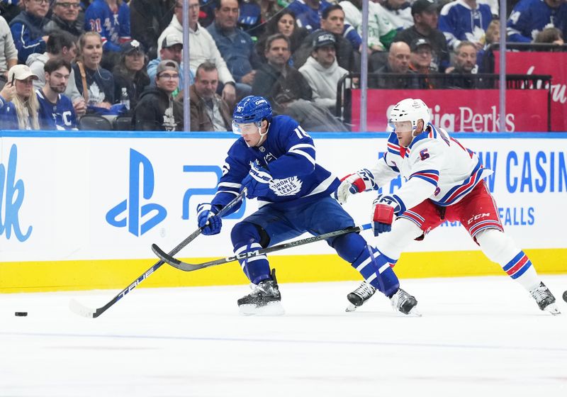 Oct 19, 2024; Toronto, Ontario, CAN; Toronto Maple Leafs right wing Mitch Marner (16) battles for the puck with New York Rangers defenseman Chad Ruhwedel (5) during the second period at Scotiabank Arena. Mandatory Credit: Nick Turchiaro-Imagn Images