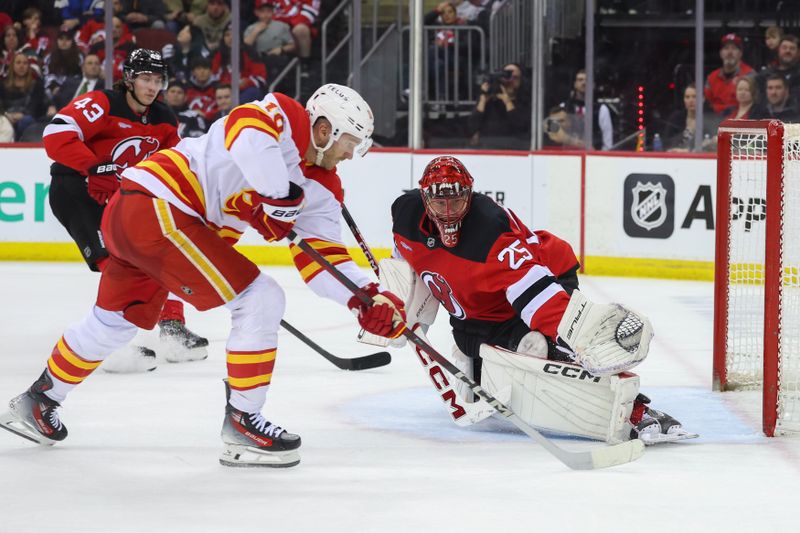 Mar 20, 2025; Newark, New Jersey, USA; New Jersey Devils goaltender Jacob Markstrom (25) makes a save on Calgary Flames left wing Jonathan Huberdeau (10) during the third period at Prudential Center. Mandatory Credit: Ed Mulholland-Imagn Images
