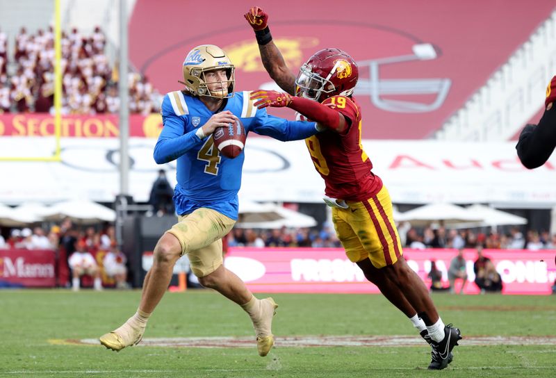 Nov 18, 2023; Los Angeles, California, USA; UCLA Bruins quarterback Ethan Garbers (4) scrambles to throw a touchdown under pressure from USC Trojans safety Jaylin Smith (19) during the third quarter at United Airlines Field at Los Angeles Memorial Coliseum. Mandatory Credit: Jason Parkhurst-USA TODAY Sports