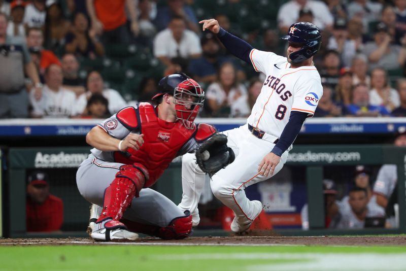 Jul 29, 2025; Houston, Texas, USA; Houston Astros first baseman Christian Walker (8) slides safely to score a run as Washington Nationals catcher Riley Adams (15) fields a throw during the first inning at Daikin Park. Mandatory Credit: Troy Taormina-Imagn Images
