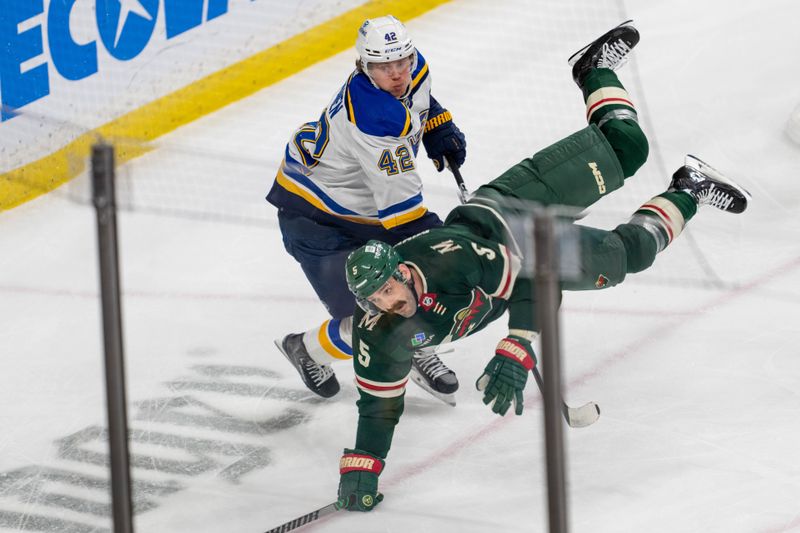 Apr 8, 2023; Saint Paul, Minnesota, USA; Minnesota Wild defenseman Jake Middleton (5) is upended by St. Louis Blues right wing Kasperi Kapanen (42) in the second period at Xcel Energy Center. Mandatory Credit: Matt Blewett-USA TODAY Sports