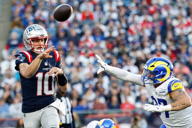 New England Patriots quarterback Drake Maye (10) flips a pass while under pressure by Los Angeles Rams linebacker Michael Hoecht (97) during the second half of an NFL football game, Sunday, Nov. 17, 2024, in Foxborough, Mass. (AP Photo/Greg M. Cooper)