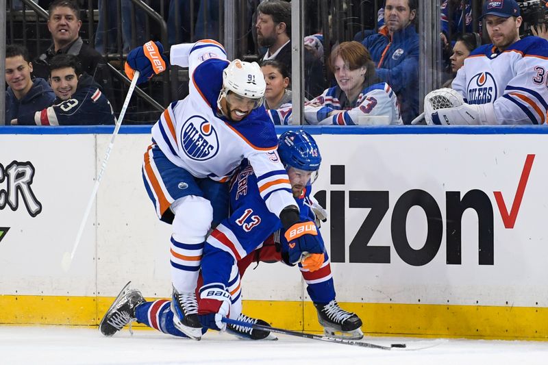 Dec 22, 2023; New York, New York, USA;  Edmonton Oilers left wing Evander Kane (91) and New York Rangers left wing Alexis Lafreniere (13) battle for a loose puck during the first period at Madison Square Garden. Mandatory Credit: Dennis Schneidler-USA TODAY Sports