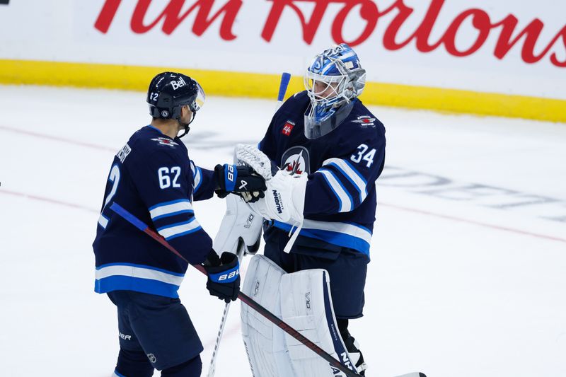 Sep 25, 2024; Winnipeg, Manitoba, CAN; Winnipeg Jets goalie Kaapo Kahkonen (34) is congratulated by Winnipeg Jets forward Nino Niederreiter (62) on his win against the Edmonton Oilers during the third period at Canada Life Centre. Mandatory Credit: Terrence Lee-Imagn Images