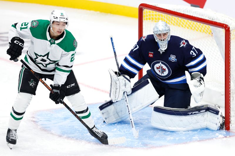 Oct 9, 2025; Winnipeg, Manitoba, CAN; Dallas Stars left wing Jason Robertson (21) waits for a shot in front of Winnipeg Jets goaltender Connor Hellebuyck (37) in the third period at Canada Life Centre. Mandatory Credit: James Carey Lauder-Imagn Images